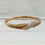A 14ct yellow gold bangle with pave set diamond band [14.89g]