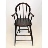 Dark stained elm wood spindle back child's highchair with turned open arm rests upon spindle legs