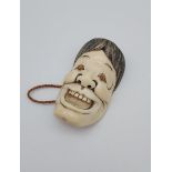 A Japanese Meiji period hand carved ivory netsuke in the form of a theatrical mask.