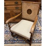 Bergere armchair, caned back with central wooden support, long open arm rests above a cushioned seat