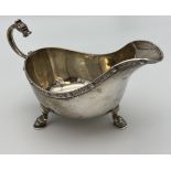 A Sheffield silver gravy boat designed with Celtic trims and dragon head handle, supported on