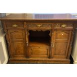 Oak dresser base, long central carved drawer above an open shelf and base cupboard, flanked by two