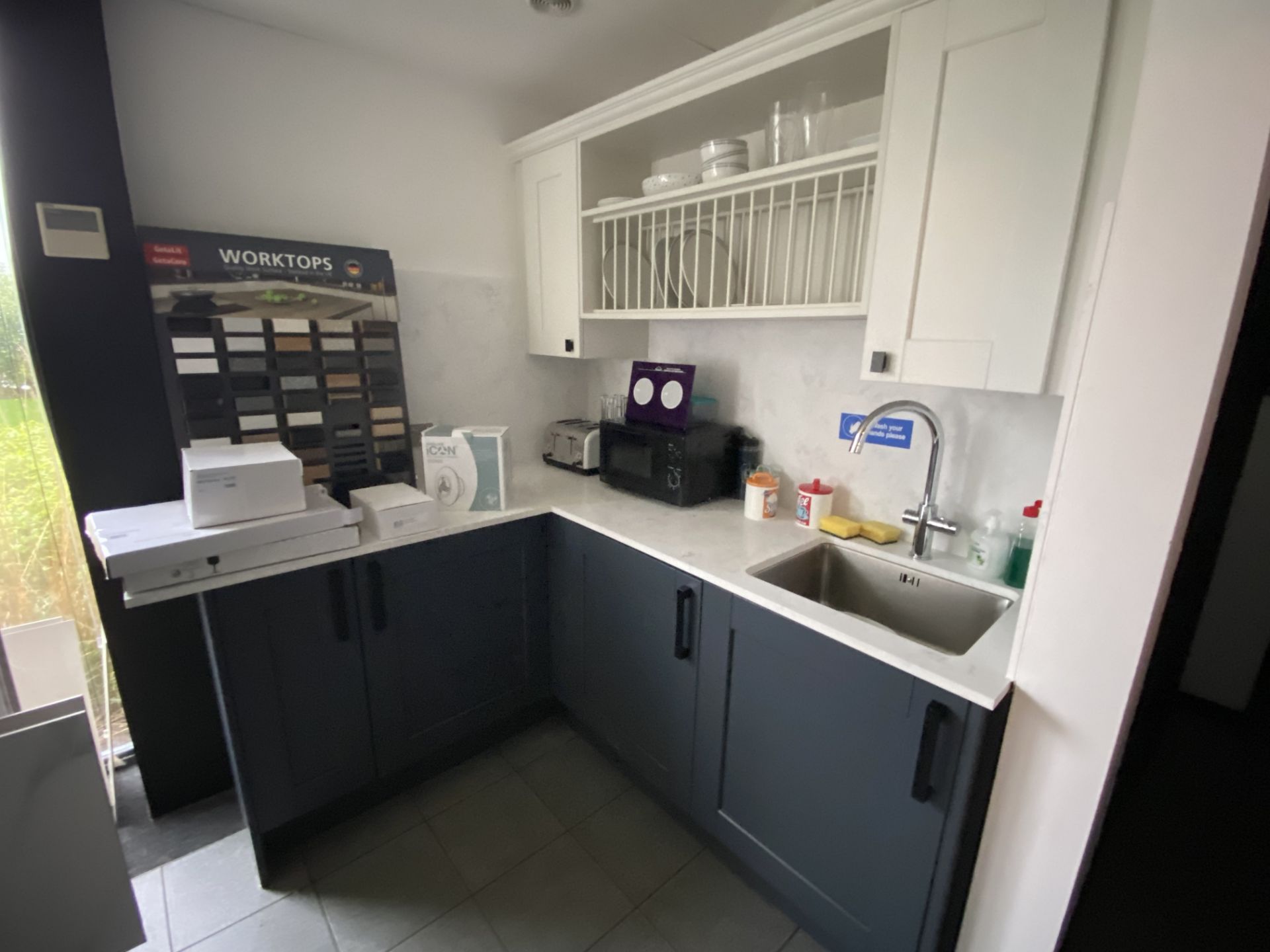 Corner kitchen units in blue/gray and white, with wall mounted plate rack and cupboards, sink, workt