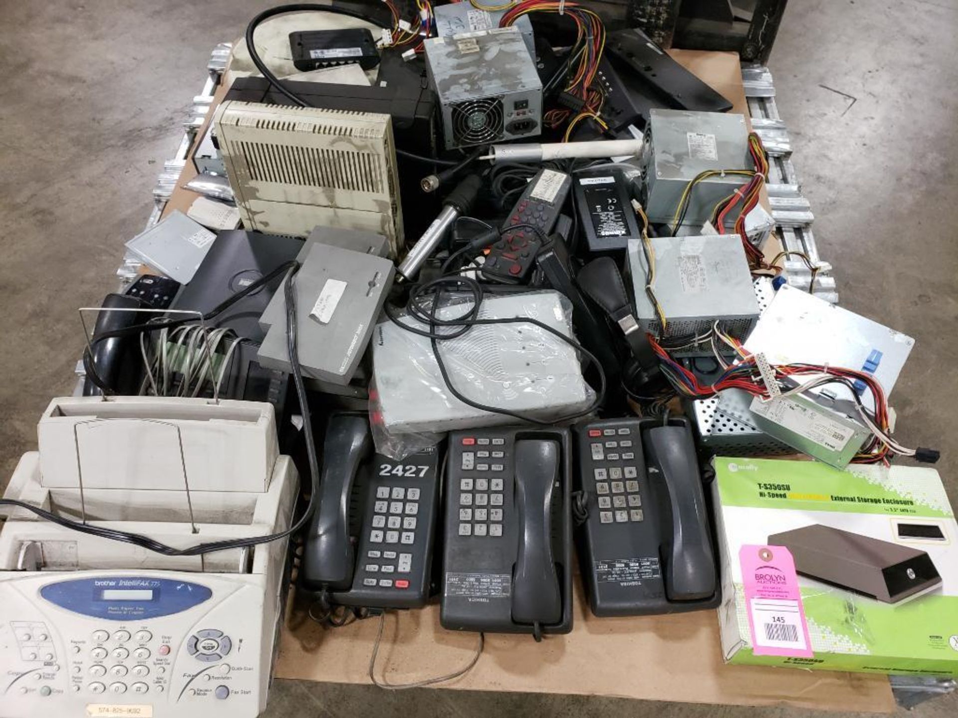 Pallet of assorted communications. Phones, fax machine. power supply. Brother, Dell.