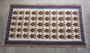 Tribal style Rug, Decorated with ten rows of five geometric motifs on an ivory ground, With a red