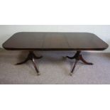 A George III style reproduction twin pedestal dining table, with turned pedestals and splay legs,