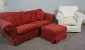 A three seater sofa and ottoman, currently upholstered in crimson, with a cream upholstered armchair