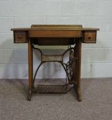 An oak cased Singer treadle sewing machine, early 20th century, with a cast iron treadle, the