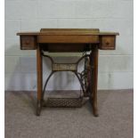 An oak cased Singer treadle sewing machine, early 20th century, with a cast iron treadle, the