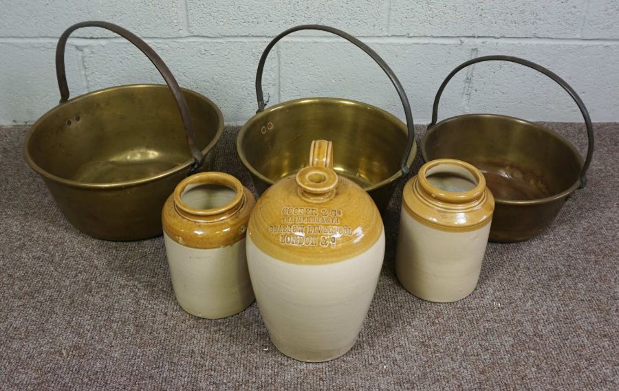 A set of three brass preserving pans, together with three stoneware vessels, including one