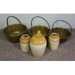 A set of three brass preserving pans, together with three stoneware vessels, including one