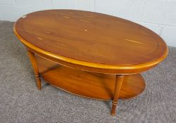 A modern Yew wood veneered two tier coffee table, the oval top set on four turned legs, 45cm high,
