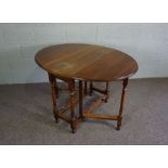 A chestnut gateleg table,  early 19th century, with plain oval drop leaf top on turned supports with