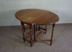 A chestnut gateleg table,  early 19th century, with plain oval drop leaf top on turned supports with