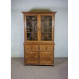 A Jacobean style oak cabinet, the top with two glazed cabinet doors enclosing shelved, over a base