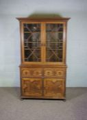 A Jacobean style oak cabinet, the top with two glazed cabinet doors enclosing shelved, over a base