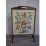 An early 20th century fire screen, the rectangular tapestry panel decorated with a spay of mixed