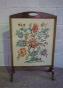 An early 20th century fire screen, the rectangular tapestry panel decorated with a spay of mixed