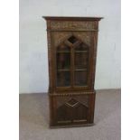 A small oak Jacobean style china cabinet, circa 1900, the top with a single glazed cabinet door,