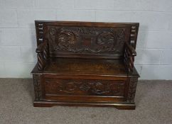 A 17th century style carved chestnut monks bench, early 20th century,  with rectangular folding top,