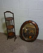 An oval veneered wall mirror, 66cm x 54cm; together with a beech three tier cake stand, 90cm high (