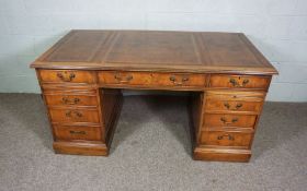 A George III style yew wood veneered writing desk, modern, with leathered top, over three frieze