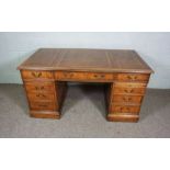 A George III style yew wood veneered writing desk, modern, with leathered top, over three frieze