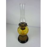 A Victorian brass and yellow glass oil lamp, with reeded spreading foot on a black ceramic foot,