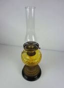 A Victorian brass and yellow glass oil lamp, with reeded spreading foot on a black ceramic foot,