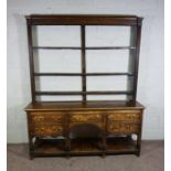An oak dresser, early 19th century, with an open plate rack, with moulded cornice and three shelves,