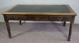 An oak library table, early 20th century, with rectangular leathered top, over three frieze