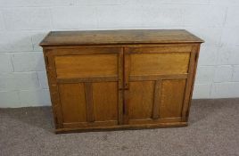 An oak side cabinet, circa 1900, with plain planked top and two panelled cabinet doors, 90cm high,