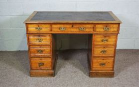 A small Edwardian oak writing desk, darkly 20th century, with a leathered top over three frieze