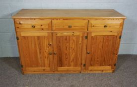 A modern varnished pine dresser base, with three drawers and three cabinet doors, 83cm wide, 135cm