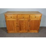 A modern varnished pine dresser base, with three drawers and three cabinet doors, 83cm wide, 135cm