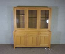 An ash wood dresser, contemporary, with three glass panelled doors opening to reveal glass