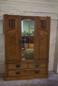 An Edwardian walnut veneered double wardrobe, circa 1900, with mirrored central door flanked by