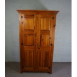 A modern varnished pine wardrobe, fitted with two panelled doors enclosing drawers and a hanging