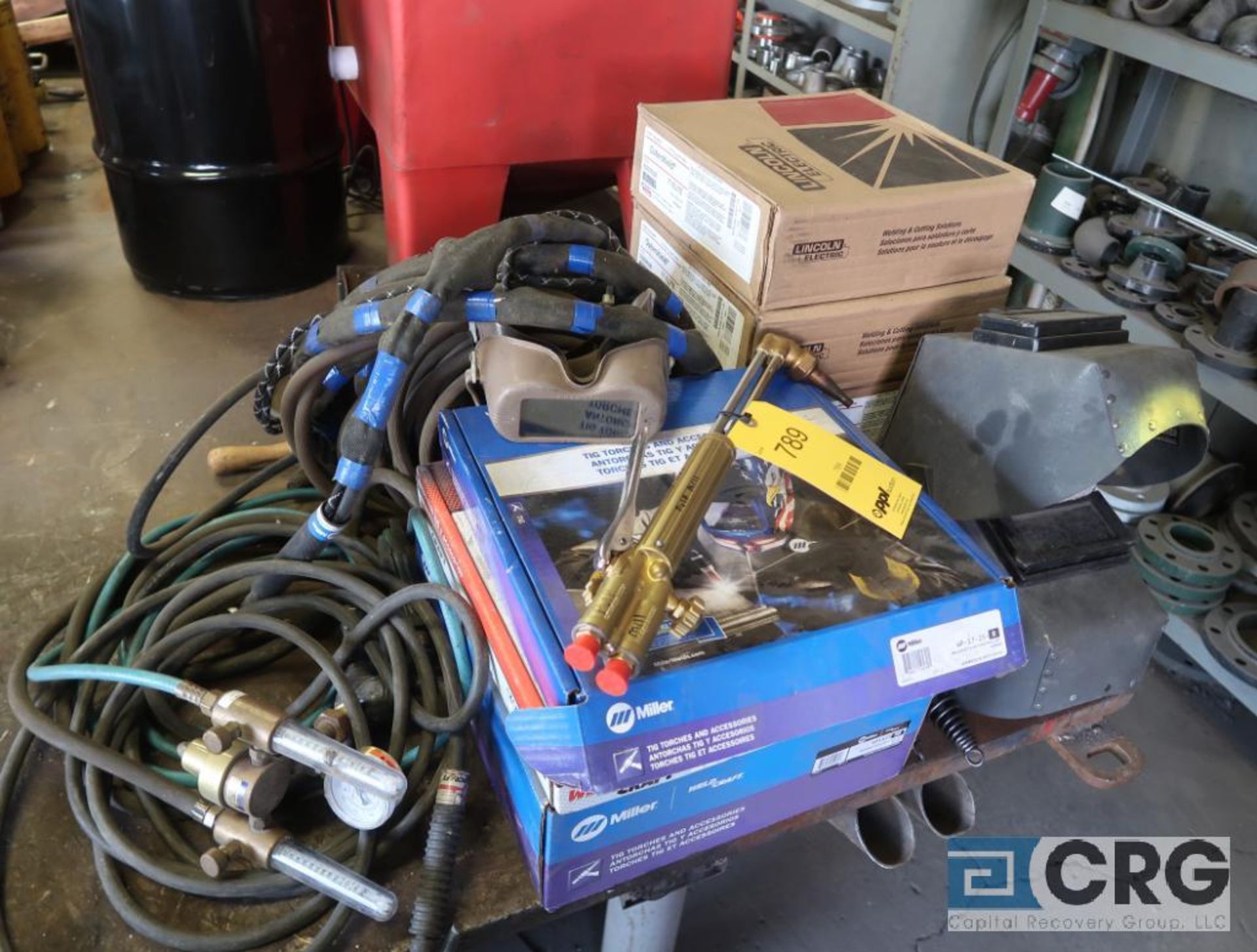Lot of assorted welding supplies including face shields, jackets, gauges, hose, and weld wire (