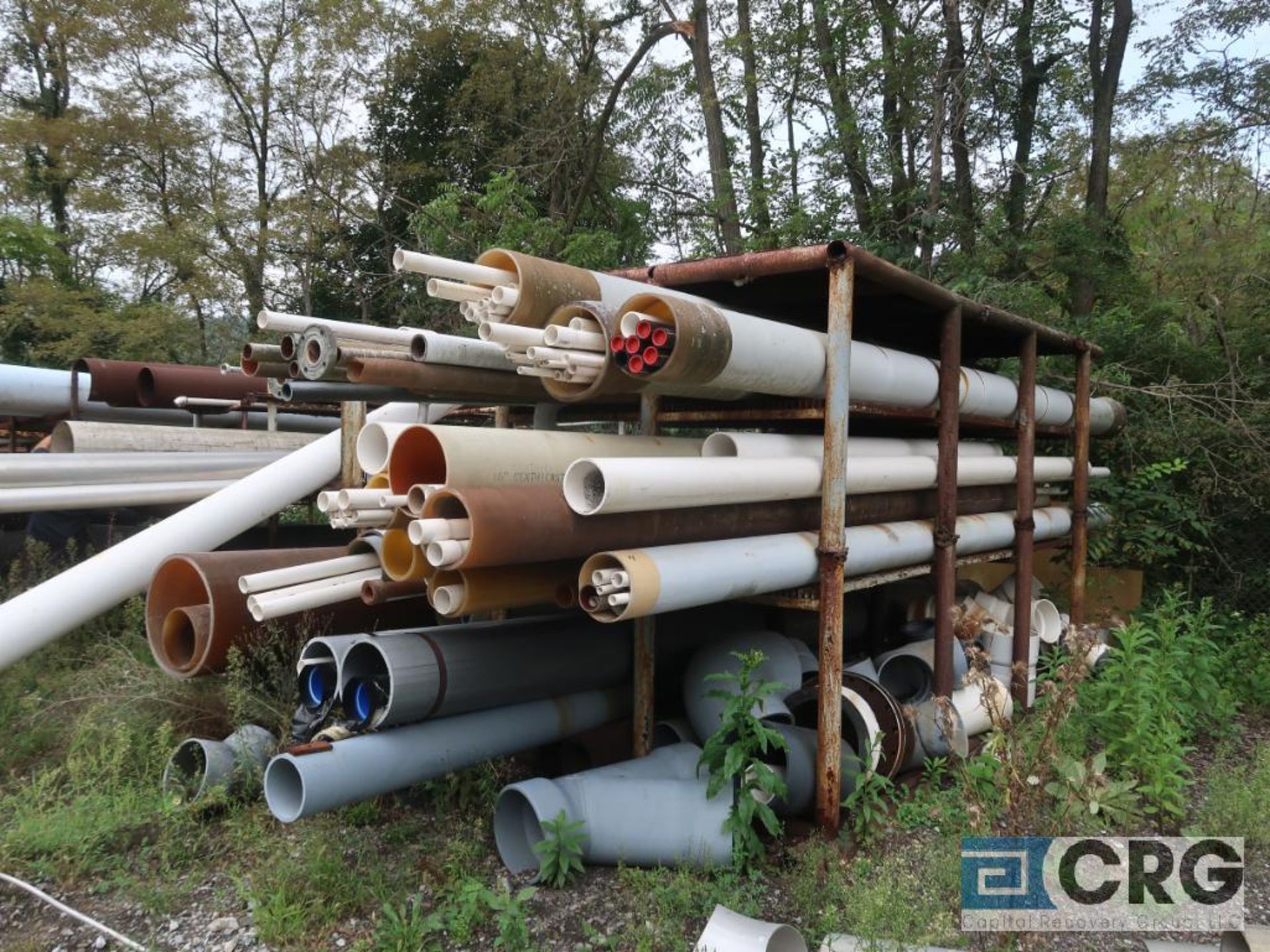 Lot of assorted pipe including steel, stainless, ABS, and PVC on racks, includes racks (Laydown