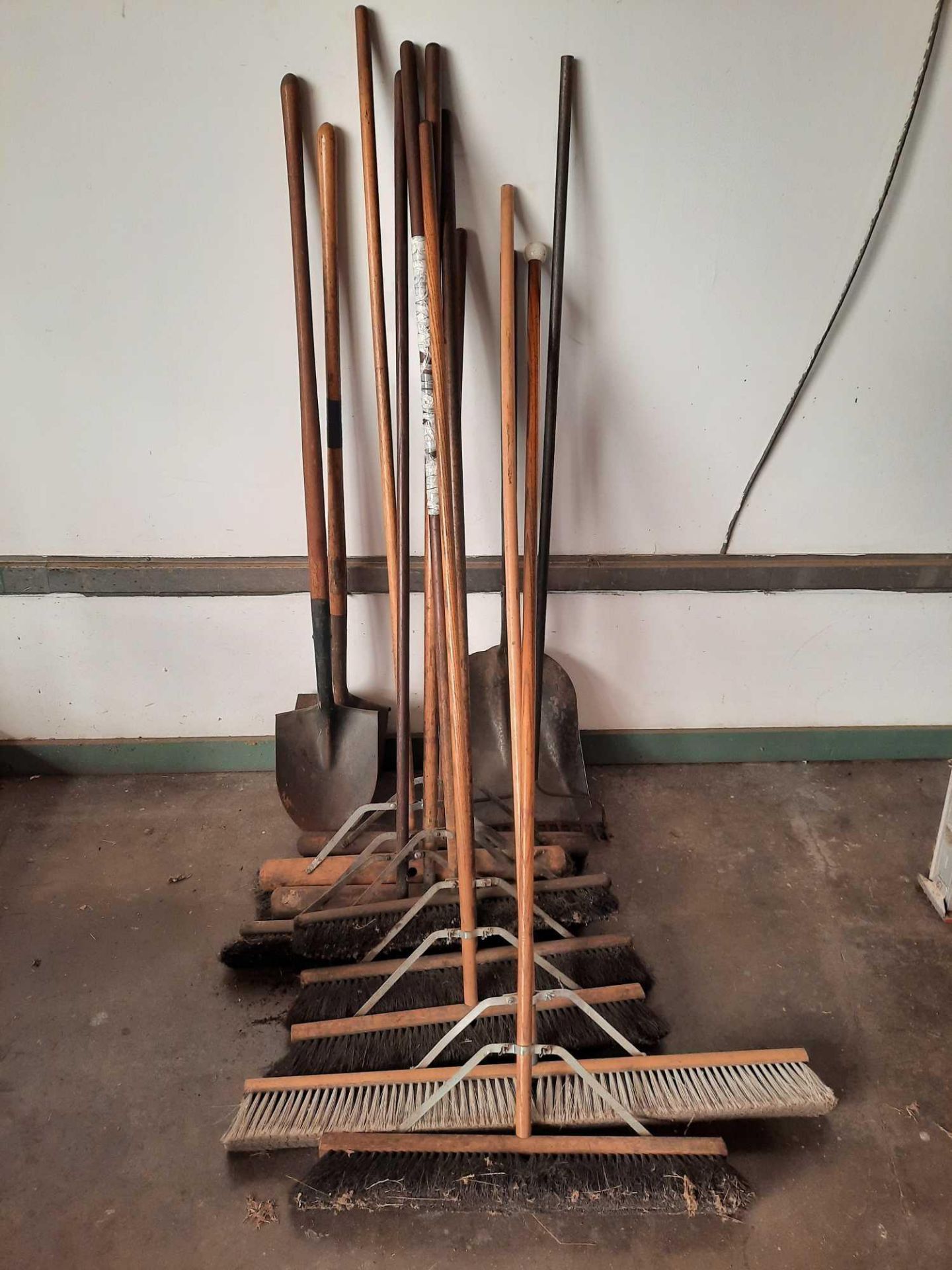 Assorted push brooms and shovels