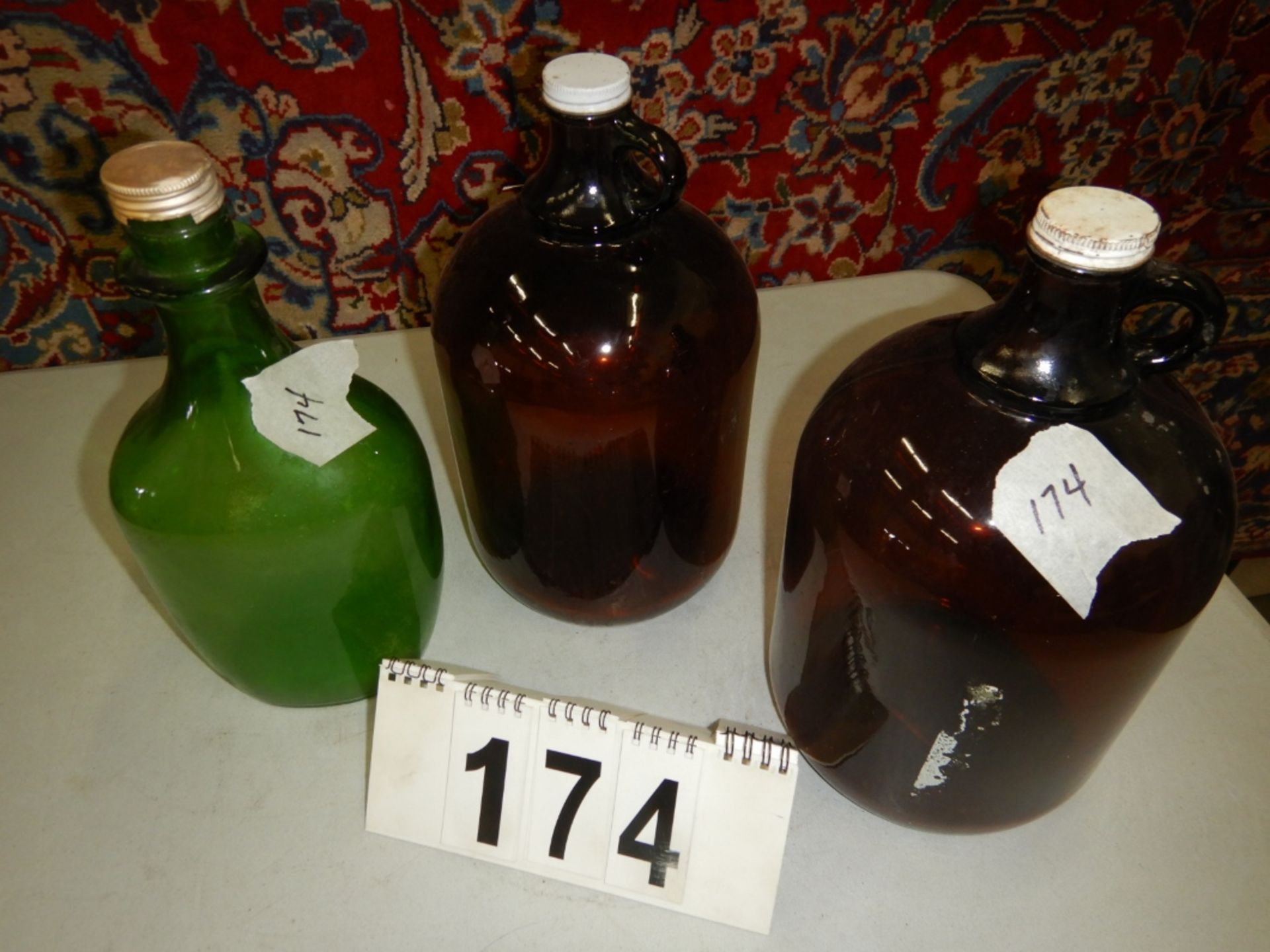 TWO BROWN GALLON JUGS WITH LIDS & ONE GREEN 1/2 GALLON JUG