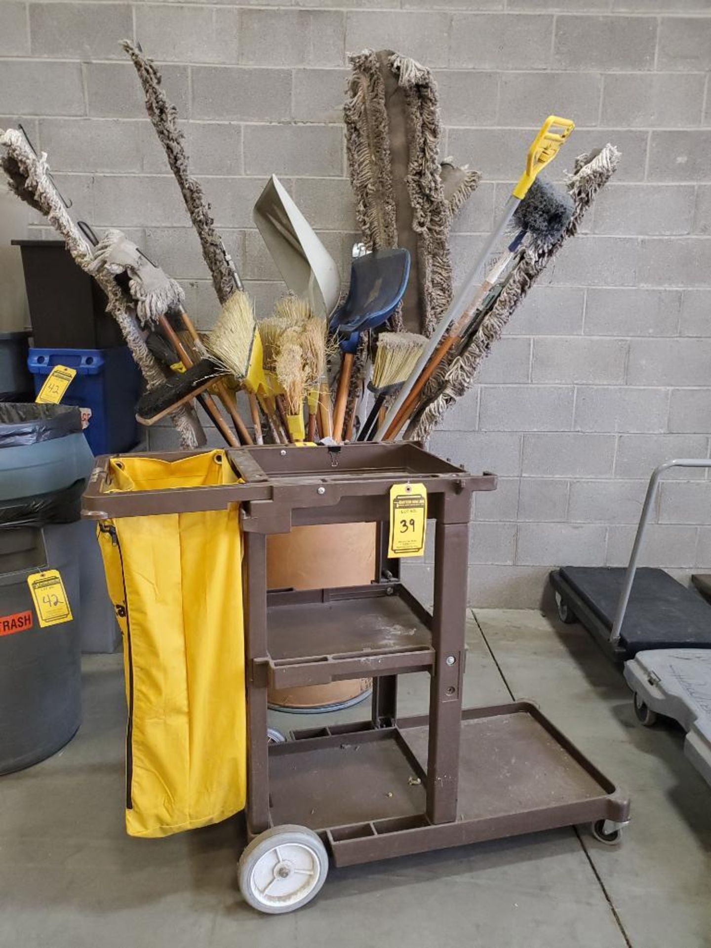 CONTINENTAL ROLLING JANITORIAL CART & CAN FULL OF BROOMS, DUSTMOPS, AND SHOVELS ***LOCATED AT