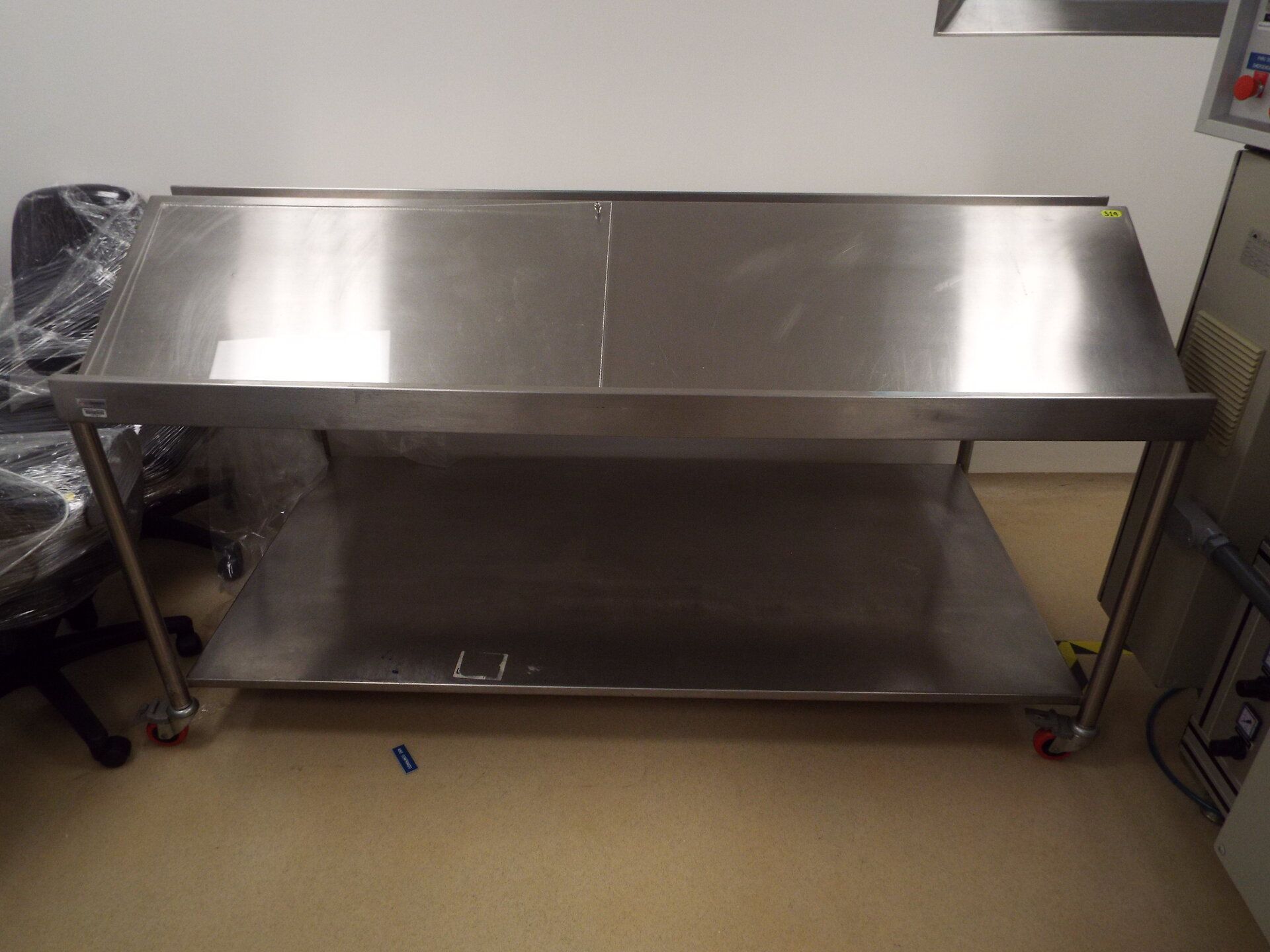 Stainless steel table with inclined panels on both sides on casters
