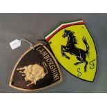 Two cast iron wall plaques, one marked Ferrari the other Lamborghini.