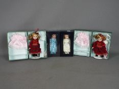Atlas Editions - Four boxed porcelain dolls on stands in various attire,