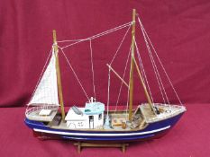 A static wooden model of a fishing vessel on a stand.