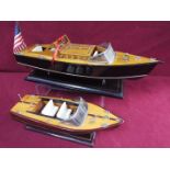 Two static wooden display models of Riva type luxury yachts.