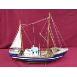 A static wooden model of a fishing vessel on a stand.