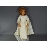 A good quality vinyl dressed doll modelled as a young girl, wearing tiara and necklace,